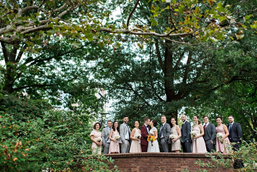 A wedding party stand on a small bridge in an old city park in Philadelphia.